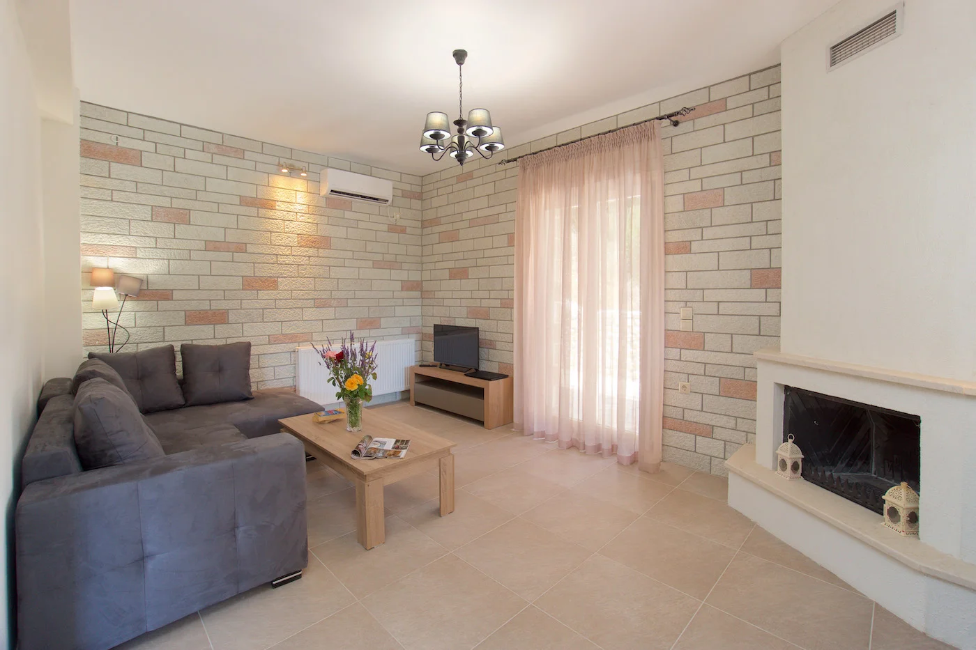 Spacious living room with stone walls and fireplace at Ariadne Villas